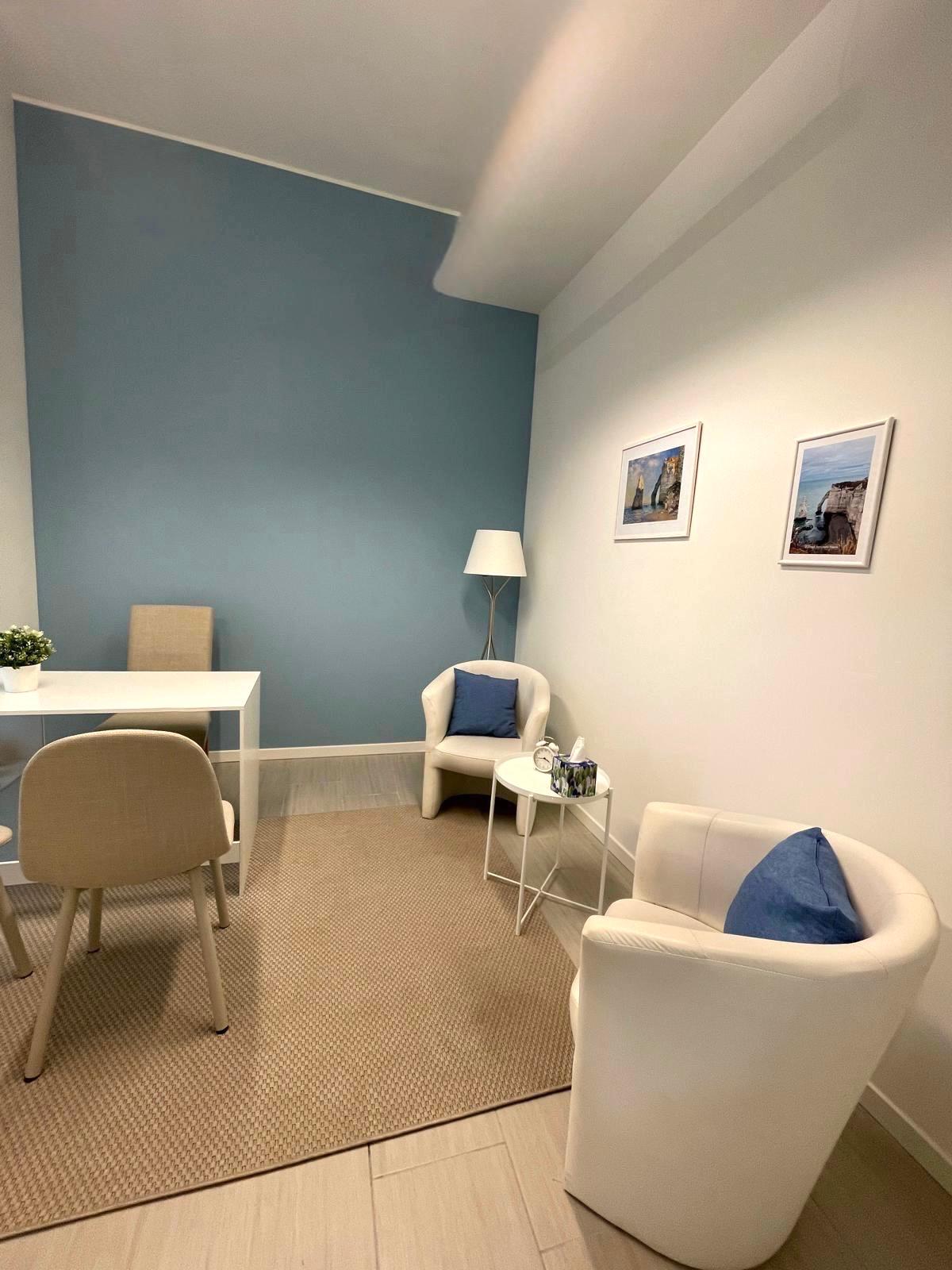 Studio Oceano: parete azzurra e poltrone bianche con cuscini blu.