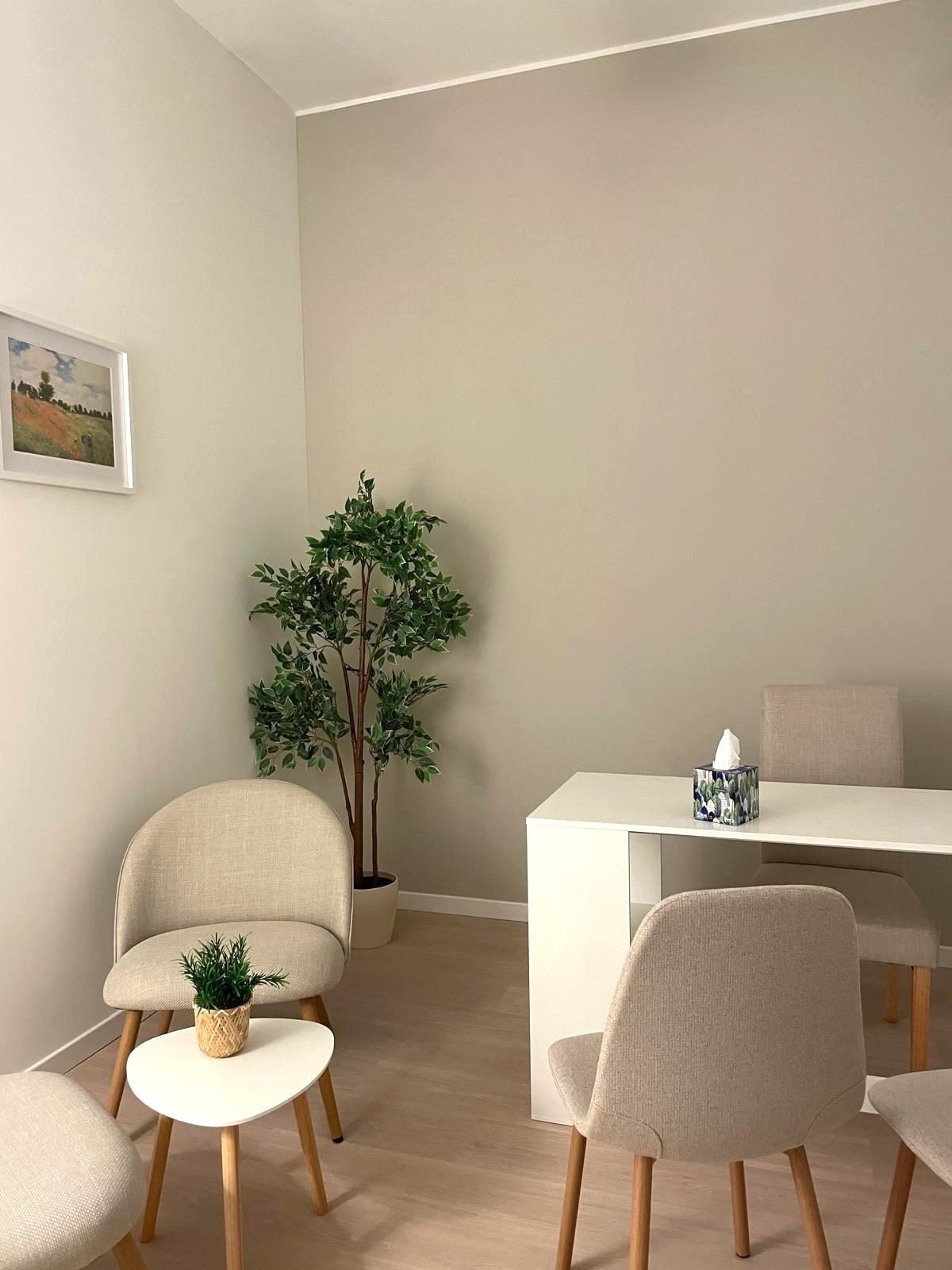 Studio Terra: arredi dai colori naturali, poltroncine e un tavolino con una pianta.